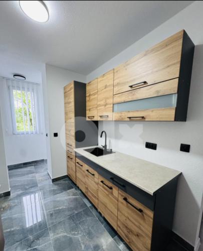 a kitchen with wooden cabinets and a sink at Stan na dan Tuzla in Tuzla