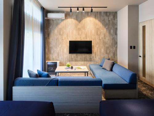 a living room with two blue couches and a tv at Minn Sapporo Odori W14 in Sapporo