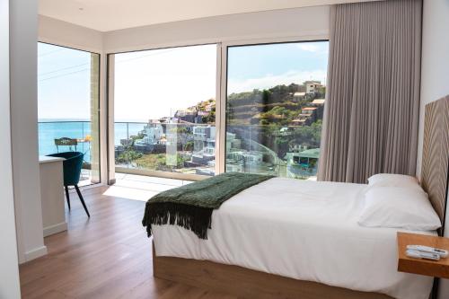 a bedroom with a large bed and a large window at Pérola de São João in Calheta