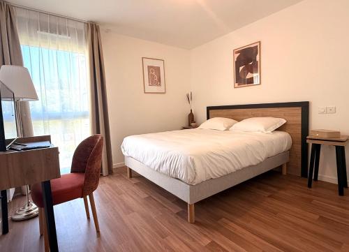 a bedroom with a bed and a desk and a chair at DOMITYS - L'Alezane in Saint Lo