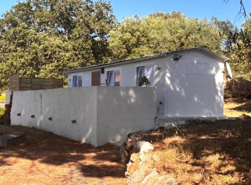 a small white shed next to a concrete wall at casa serena in Lumio