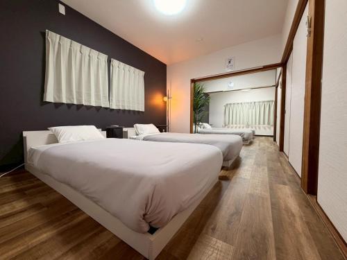two beds in a hotel room with a mirror at ura 花れ -hanare- in Okayama