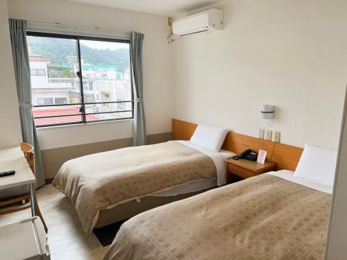 a hotel room with two beds and a window at Hotel Yamadaso in Nago