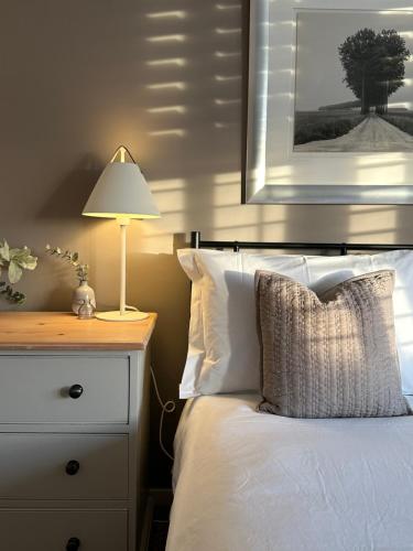 a bedroom with a white bed with a lamp on a dresser at The Old Bell B&B in Grimston