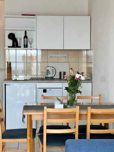a kitchen with a table with a vase of flowers at Apartments Vujic in Mirce