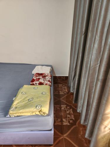 a bed with a blanket on it next to a curtain at TANJIL RESTAURANT & Guesthouse in Phnom Penh