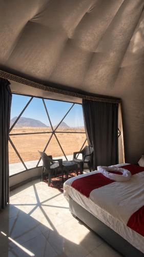 a bedroom with a bed and a view of the desert at FLORA RUM LUXURY CAMP & Bubble Hotel in Wadi Rum