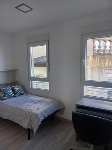 a bedroom with a bed and two windows at Casa de la Soledad 2 in Lugo