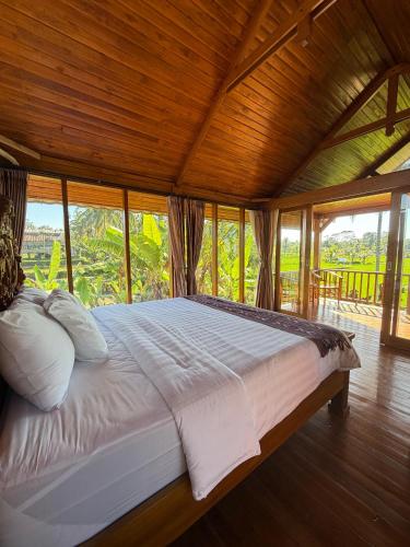 a large bed in a room with windows at The BENAWAH Villa in Tegalalang