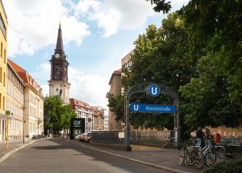 a street sign in a city with a clock tower at Limehome Berlin Klosterstraße in Berlin