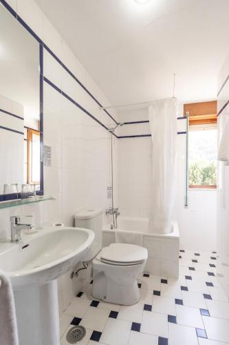 a white bathroom with a toilet and a sink at Pension Monteverde in Cangas de Onís