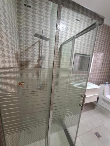 a shower with glass doors in a bathroom at Kigali Great Garden in Kigali