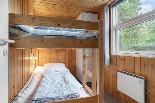 two bunk beds in a wooden room with a window at 30586-Odder-Tvaeragervej-7 in Odder