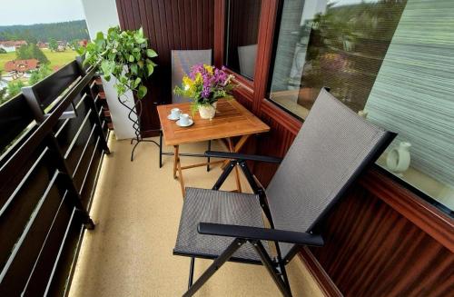 a chair and a table on a balcony with flowers at Fewo Schwarzwald Von Oben - Kniebis in Freudenstadt