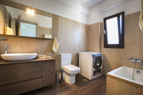 a bathroom with a toilet and a sink and a mirror at Villa Karavias by Villa Select in Trapezaki