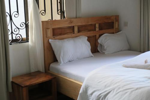 two beds with white pillows and a headboard in a room at Chama Haven Appartment 2 bed in Tengeru