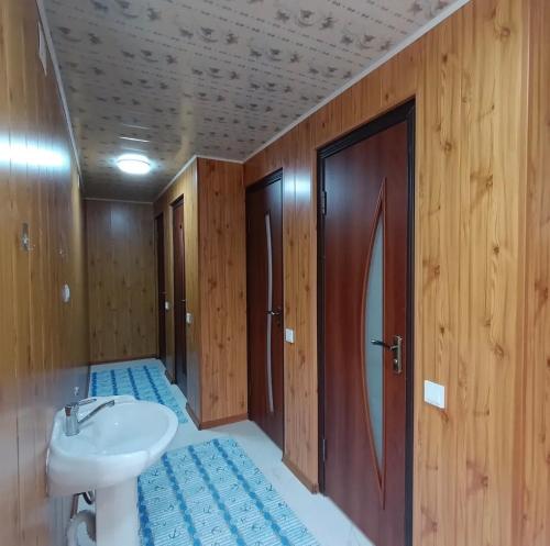a bathroom with a sink and a toilet and wooden walls at Guesthouse'Hadicha' in Tong