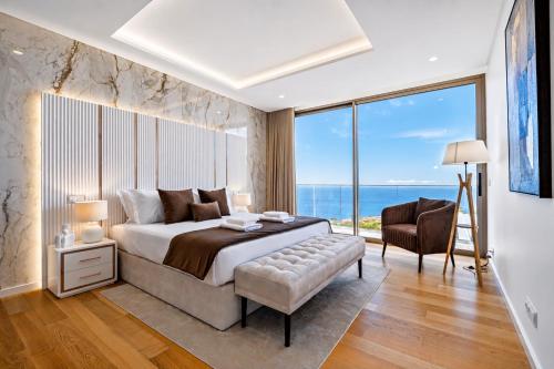 a bedroom with a bed and a chair and a large window at Villa Platinum by Homie in Estreito da Calheta