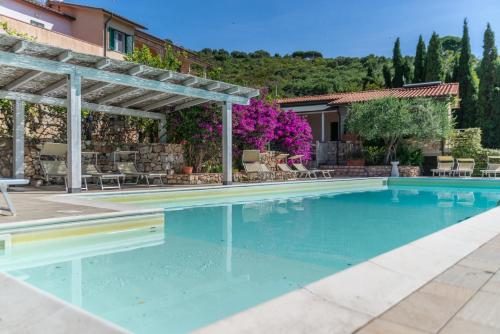 a swimming pool with a pergola and a house at Appartamenti Le Solane - Goelba in Marmi