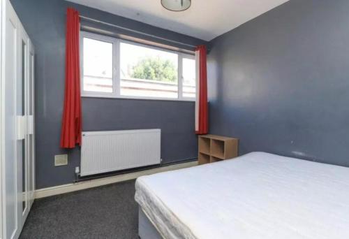 a bedroom with a bed and a window with red curtains at Beach Next Door Flat Retreat and Free Parking in Margate