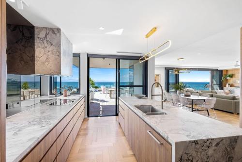 a kitchen with marble counter tops and a living room at Penthouse at First Bay Coolum in Coolum Beach