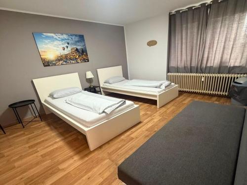 two beds in a room with wooden floors at Work & Stay apartments Solingen in Solingen
