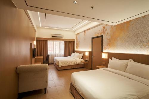 a hotel room with two beds and a chair at BTC Hotel 比特币酒店 in Malacca