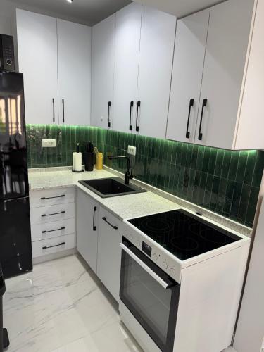 a kitchen with white cabinets and a stove top oven at Stylish Ohrid Apartment, Hot Tub, Steps to Lake in Ohrid