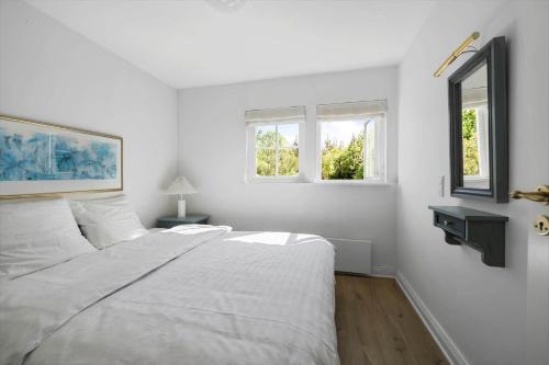 a white bedroom with a bed and two windows at 1061-N-Vejby-Lundebakken-1 in Vejby