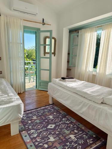 a room with two beds and a door to a patio at LAGO Skiathos Guest Suites in Skiathos