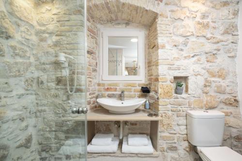a stone bathroom with a sink and a toilet at Corfu Breeze Liston Apartments in Corfu