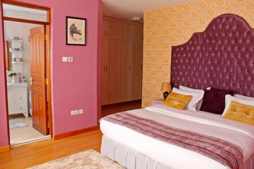 a bedroom with a large bed with a large headboard at Salmiya Place in Nairobi