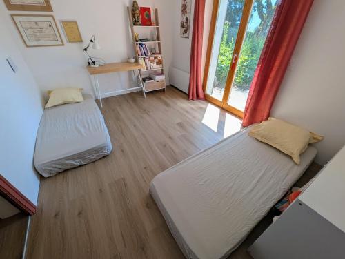 two beds in a room with a window at Chambres indépendantes chez l'habitant in Saint-Pierre-dʼAlbigny