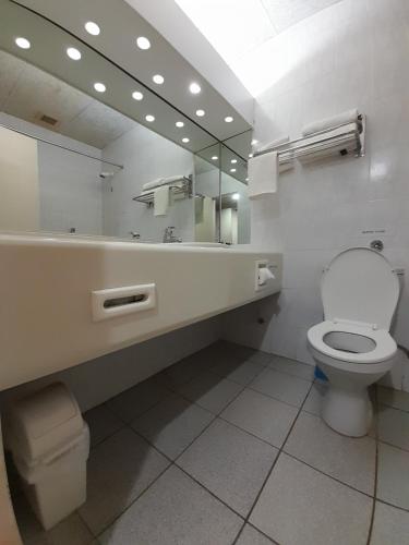 a bathroom with a toilet and a large mirror at Matsapha Hotel in Mahlanya