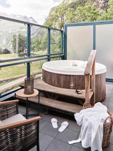 a bath tub on a deck with a view of a mountain at Hotel Union Geiranger Resort & Spa in Geiranger