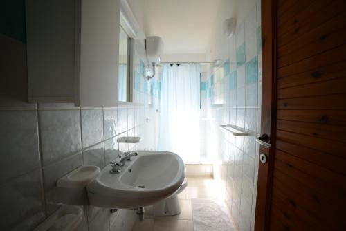 a white bathroom with a sink and a window at Villaggio Sa Ventana in Badesi