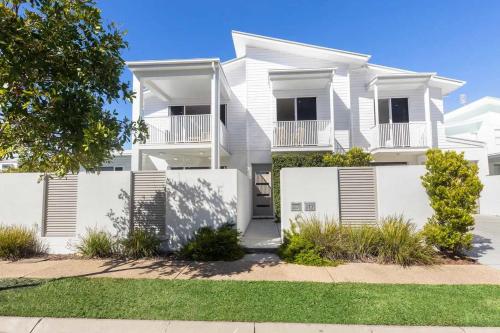 a white house with a fence in front of it at Waves Beach House in Marcoola