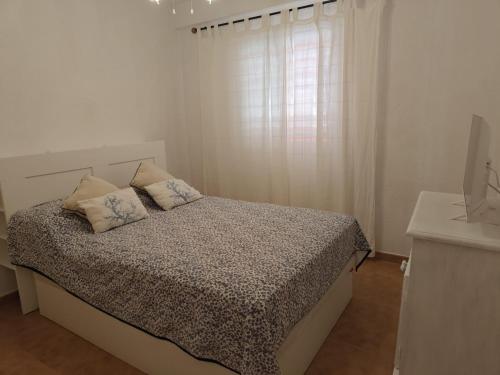 a white bedroom with a bed and a window at Rinconcito Roteńo in Rota