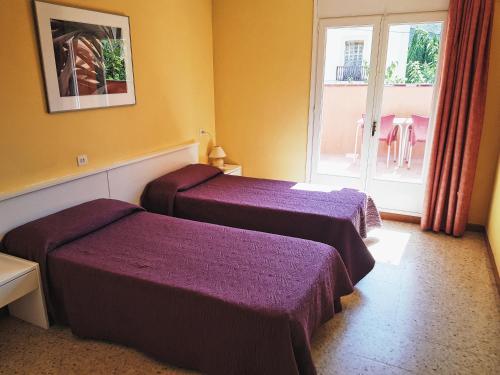 a hotel room with two beds and a window at Hostal Lara in Llança