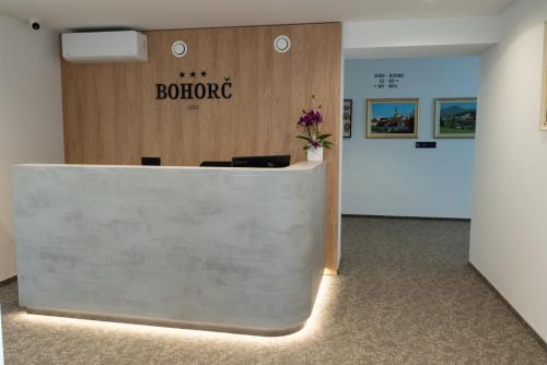 a reception desk in an office with a sign on the wall at Superior Rooms Bohorč in Šentjur