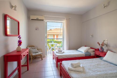 a bedroom with two beds and a window with a chair at Hotel Asimina Laganas in Laganas