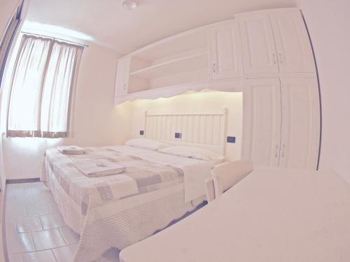 1 dormitorio blanco con 1 cama blanca grande y espejo en Albergo Bel Soggiorno, en Fiumalbo