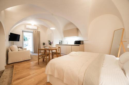 a white bedroom with a bed and a kitchen at Vila Dolná in Banská Bystrica
