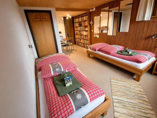 two beds are in a room with a book shelf at "Mon Rêve" Nature, Tranquility & Lake Thun in Sigriswil