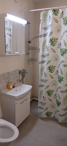 a bathroom with a shower curtain with a toilet and a sink at Saimaa Parkview Luxury Suite in Savonlinna