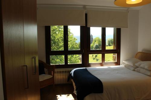 a bedroom with a bed and two windows with trees at Casa Rural Balerdi in Azcárate