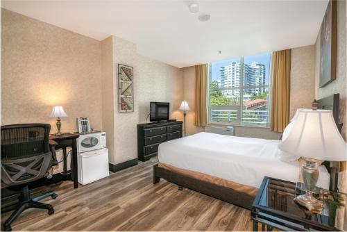 a hotel room with a bed and a desk and a computer at Coast Lonsdale Quay Hotel in North Vancouver