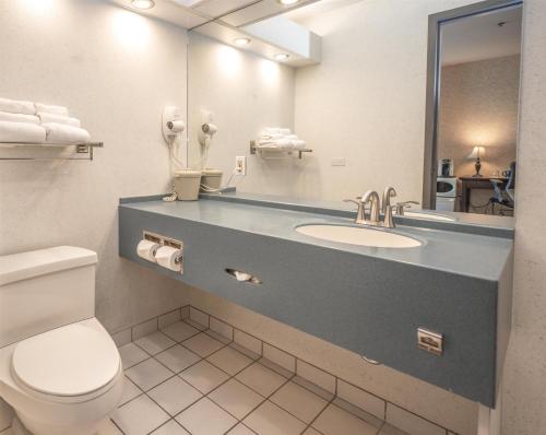 a bathroom with a sink and a toilet and a mirror at Coast Lonsdale Quay Hotel in North Vancouver