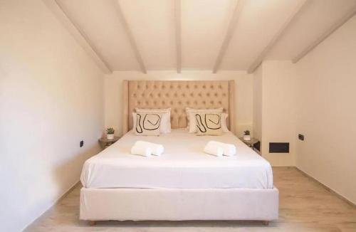 a white bedroom with a large white bed with two pillows at Greenery Luxury Apartment in Potamós