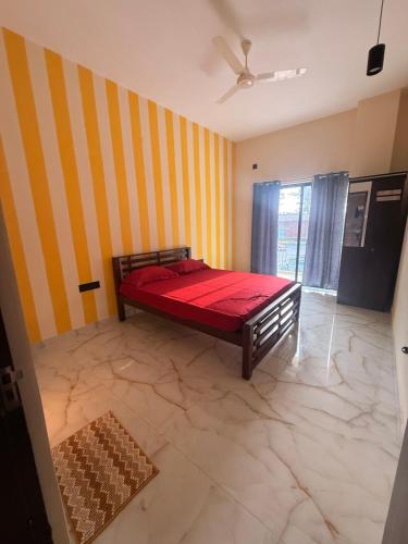 a bedroom with a red bed and a striped wall at Golden rays beach stay in Mangalore